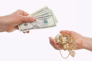 Two hands exchanging money on golden jewelry